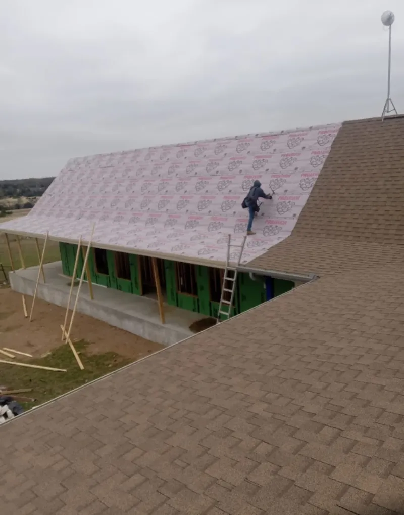 Worker preparing underlayment for a metal roof installation in Frederick